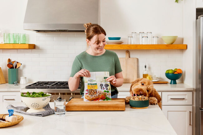 Woman feeding her dog Freshpet